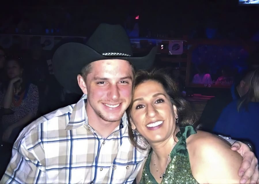 This image provided by Joey Reed, shows Trevor Reed and his mom Paula Reed in 2014 in Arlington, Texas. The parents of Reed, a former U.S. Marine who has been jailed for nearly a year in Moscow on charges that he assaulted police officers, are urging the court system and government to ensure a fair trial for their son. The parents of Trevor Reed spoke Monday to The Associated Press as a Russian court sentenced another American man to more than a decade in prison in an unrelated espionage case.
