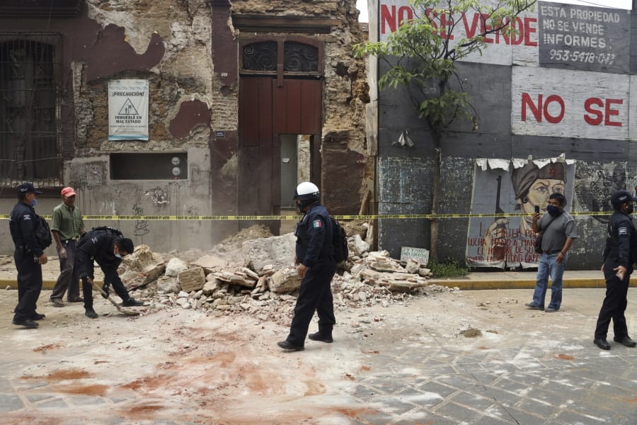 A policeman removes rubble from a building damaged by an earthquake in Oaxaca, Mexico, Tuesday, June 23, 2020. The earthquake was centered near the resort of Huatulco, in the southern state of Oaxaca.