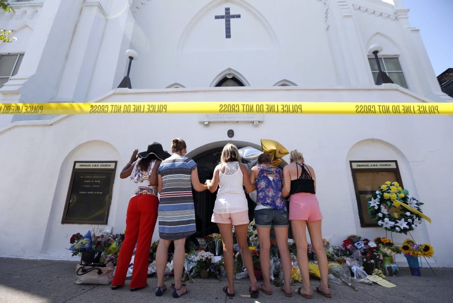 FILE - In this June 18, 2015, file photo, a group of women pray at a makeshift memorial on the sidewalk in front of the Emanuel AME Church in Charleston, S.C. One big change happened in conservative South Carolina after a racist gunman killed nine black people during a Bible study five years ago, the Confederate flag came down. But since then, hundreds of other monuments and buildings named for Civil War figures, virulent racists and even a gynecologist who did painful, disfiguring medical experiments on African American women remain. (AP Photo/Stephen B.