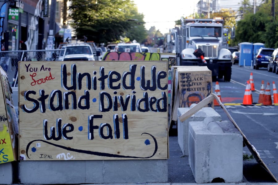 A sign on a barricade reads &quot;United we stand divided we fall,&quot; as a truck and other heavy equipment from the Seattle Department of Transportation is staged at the the CHOP (Capitol Hill Occupied Protest) zone in Seattle, Friday, June 26, 2020. Workers arrived with the intention of removing barricades that had been set up in the area and were met with opposition from protesters. Several blocks in the area have been occupied by protesters since Seattle Police pulled back from their East Precinct building following violent clashes with demonstrators earlier in the month. (AP Photo/Ted S.