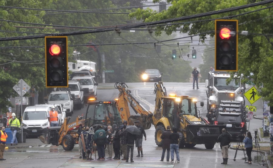 Seattle Department of Transportation workers remove barricades at the intersection of 10th Ave. and Pine St., Tuesday, June 30, 2020 at the CHOP (Capitol Hill Occupied Protest) zone in Seattle. Protesters quickly moved couches, trash cans and other materials in to replace the cleared barricades. The area has been occupied by protesters since Seattle Police pulled back from their East Precinct building following violent clashes with demonstrators earlier in the month. (AP Photo/Ted S.