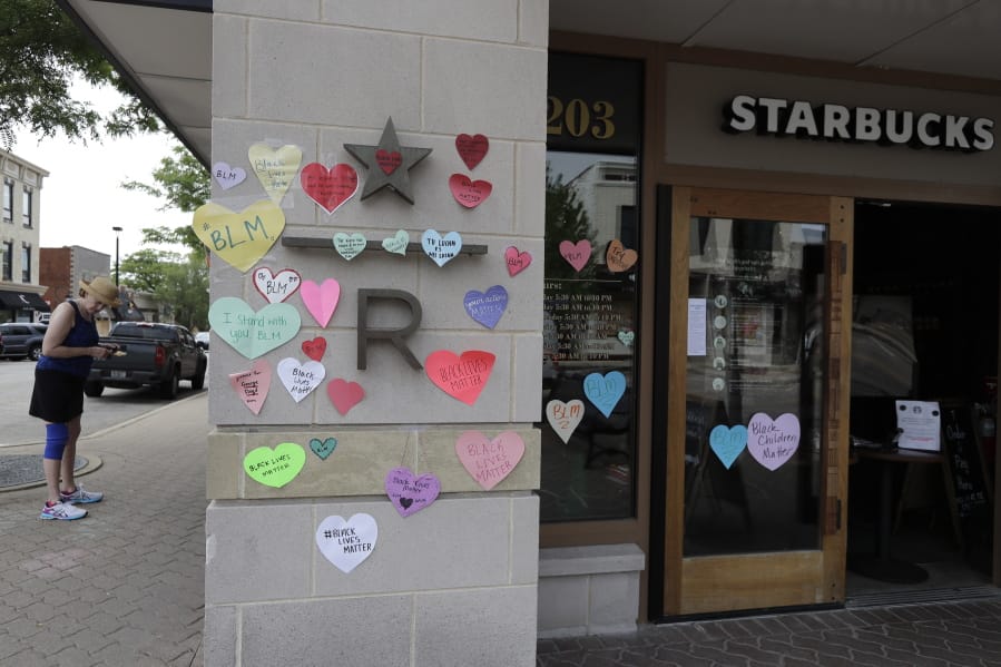FILE - In this Thursday, June 4, 2020 file photo, a woman looks at the plywood covering the windows of a Starbucks store in downtown Naperville, Ill., as Naperville residents used hearts to post messages in support of the Black Lives Matter movement. Starbucks is the latest company to say it will pause social-media ads after a campaign led by civil-rights organizations called for an ad boycott of Facebook, saying it doesn&#039;t do enough to stop racist and violent content.  Starbucks said Sunday, June 28 that its actions were not part of the &quot;#StopHateforProfit&quot; campaign, but that it is pausing its social ads while talking with civil rights organizations and its media partners about how to stop hate speech online.  (AP Photo/Nam Y.