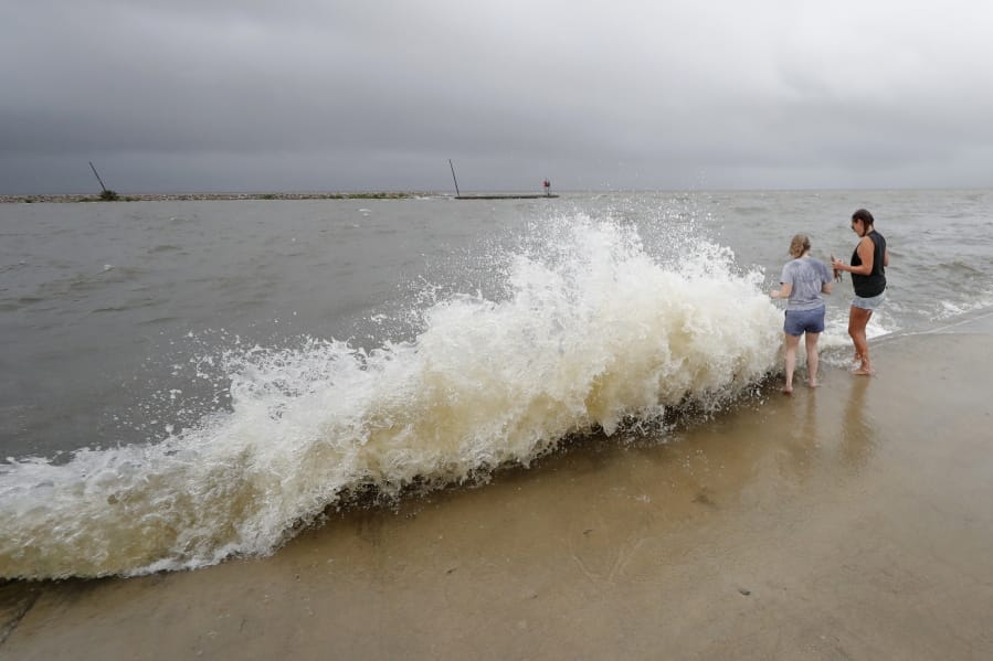 Erin Shaw, left, and Brittany Schanzbach stand near crashing waves near the seawall of Lake Pontchartrain from a storm surge in New Orleans, Sunday, June 7, 2020, as Tropical Storm Cristobal approaches the Louisiana Coast.