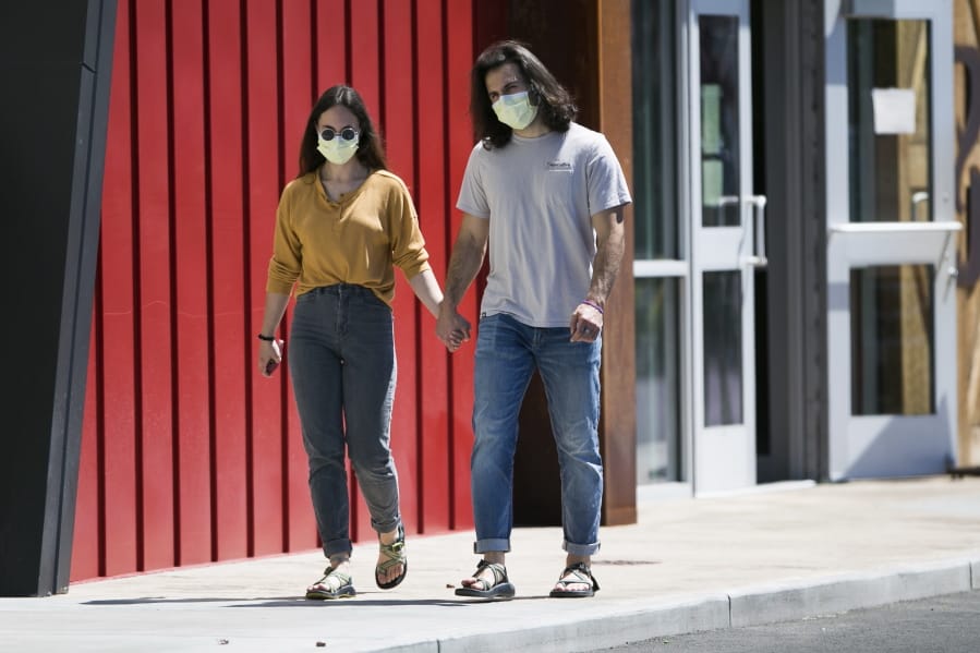Hana Morris, left, and Forrest Golic wear masks as they walk hand in hand Monday, June 22, 2020, in Yakima.