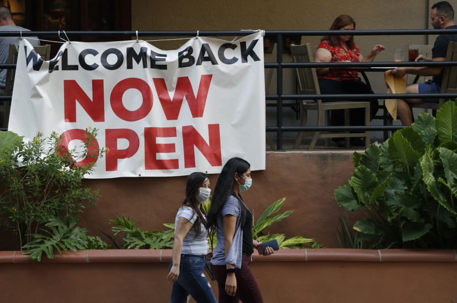 FILE - In this May 27, 2020, file photo, visitors to the River Walk pass a restaurant that has reopened in San Antonio. Coronavirus cases are rising in nearly half the U.S. states, as states are rolling back lockdowns.