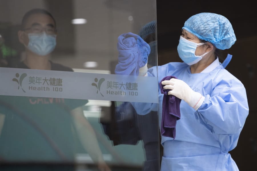A worker cleans the glass door to a health center for COVID-19 testing in Beijing on Wednesday, June 17, 2020. The Chinese capital on Wednesday canceled more than 60% of commercial flights and raised the alert level amid a new coronavirus outbreak, state-run media reported.