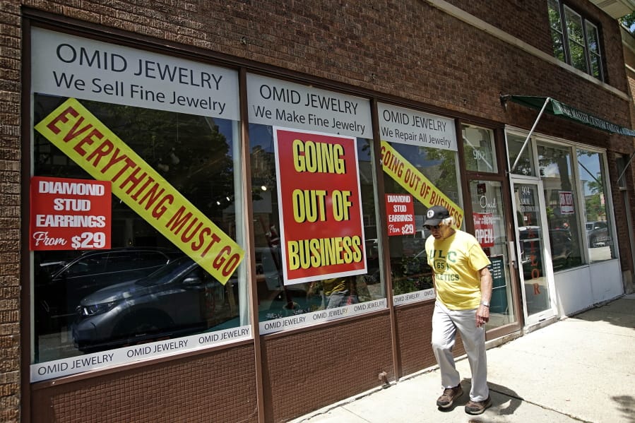 A man walks past a retail store that is going out of business due to the coronavirus pandemic in Winnetka, Ill., Tuesday, June 23, 2020. Illinois Gov. J.B Pritzker announced a package of state grant programs that will help support communities and businesses impacted by the COVID-19 pandemic and unrest in the area. (AP Photo/Nam Y.