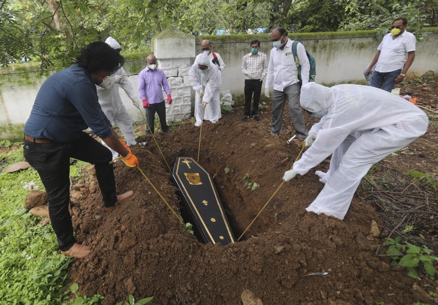 People lower the coffin of a man who died of COVID-19, at a cemetery in Mumbai, India, Tuesday, June 23, 2020. Some Indian states Tuesday were considering fresh lockdown measures to try to halt the spread of the virus in the nation of more than 1.3 billion.