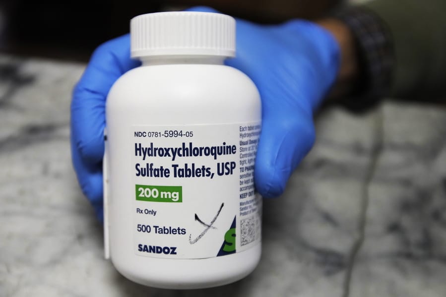 FILE - In this April 6, 2020 file photo, a pharmacist holds a bottle of the drug hydroxychloroquine in Oakland,  (AP Photo/Ben Margot)