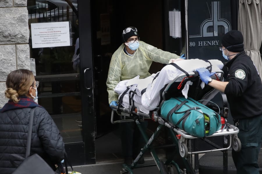 FILE- In this April 17, 2020, file photo, a patient is wheeled into Cobble Hill Health Center by emergency medical workers in the Brooklyn borough of New York. A grim blame game with partisan overtones is breaking out over COVID-19 deaths among nursing home residents, a tiny slice of the population that represents a shockingly high proportion of Americans who have perished in the pandemic.