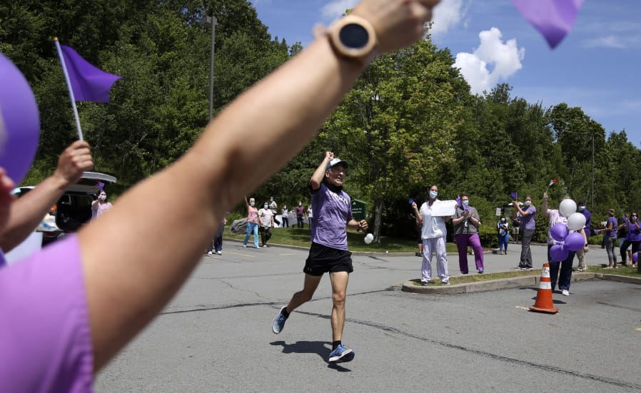 Nursing home workers cheer as Corey Cappelloni completes his seventh ultramarathon in seven days in Scranton, Pa., Friday, June 19, 2020. Cappelloni ran roughly 218 miles from Washington, D.C., to Scranton to visit his 98-year-old grandmother and raise awareness for older adults in isolation amid the coronavirus pandemic.