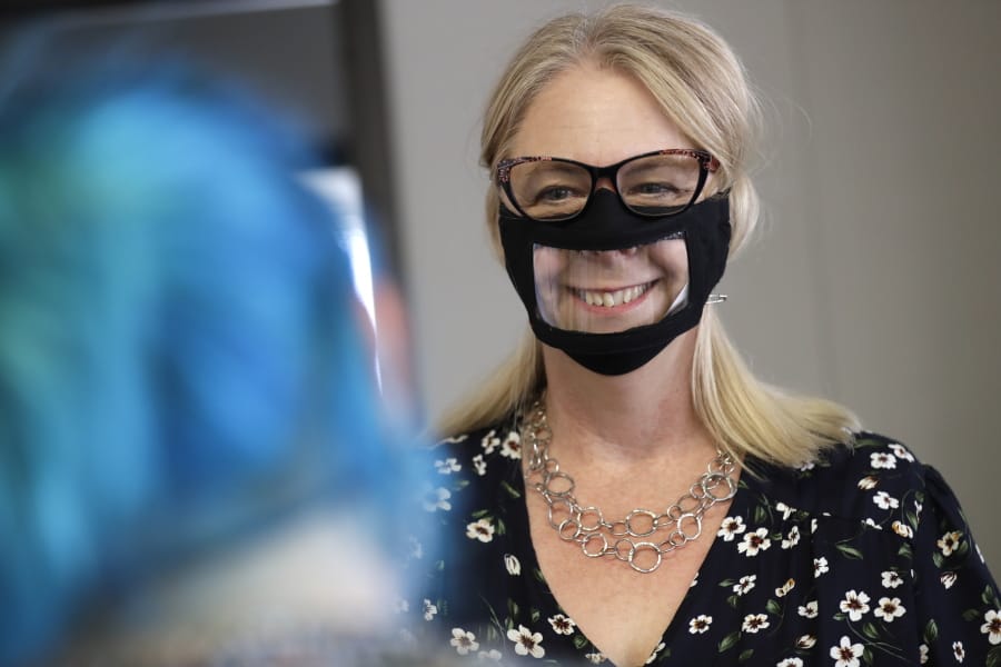 In this June 3, 2020, photo, Chris LaZich, of Fleet Science Center, wears a mask with a window as she talks with Delpha Hanson in San Diego.