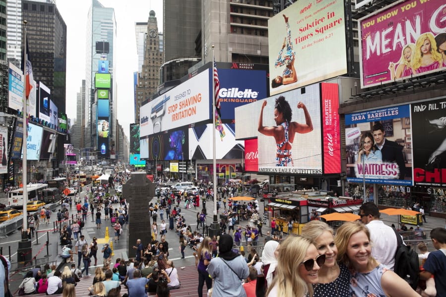 FILE - In this June 20, 2019, file photo, tourists visit Times Square in New York. After three months of a coronavirus crisis followed by protests and unrest, New York City is trying to turn a page when a limited range of industries reopen Monday, June 8, 2020.