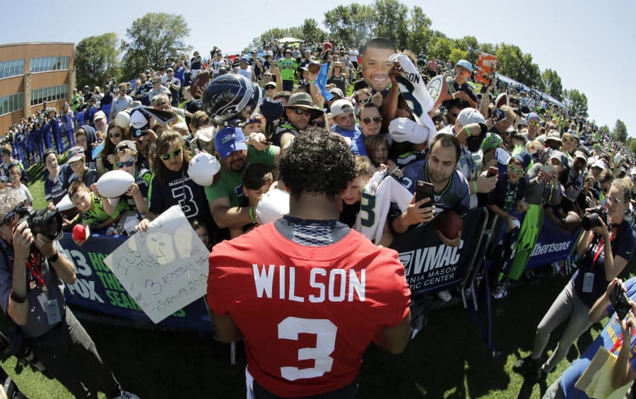Seattle Seahawks quarterback Russell Wilson (3) signs autographs for fans following a training camp session in 2019 at Renton. The NFL is telling the Seahawks and all other teams training camps for 2020 are on. For Seattle, rookies report on July 21, and all other players on July 28. (AP Photo/Ted S.