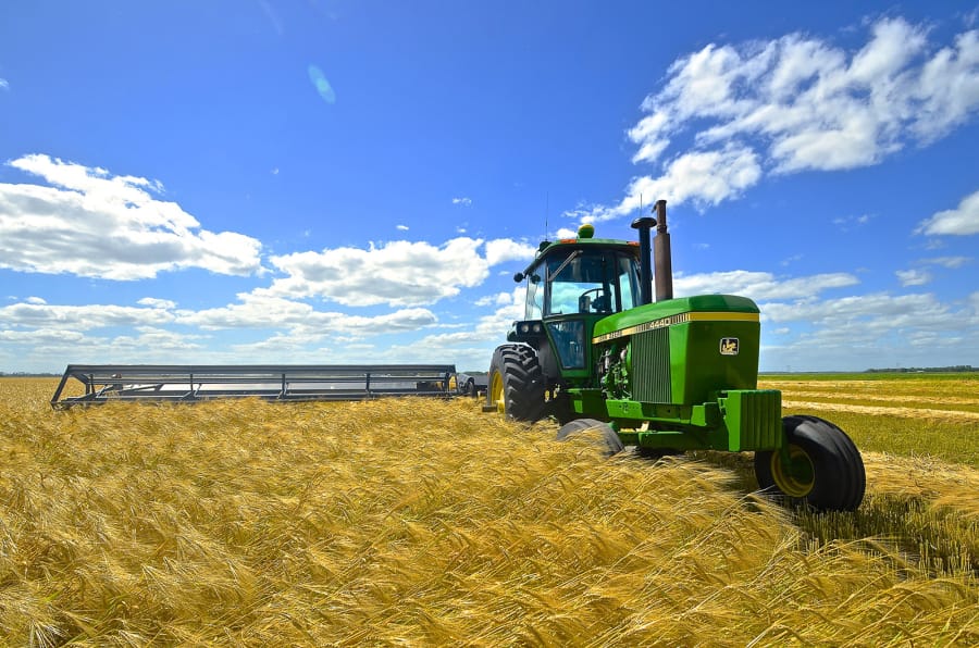 A John Deere 4440 tractor and swather cutting wheat in North Dakota. Worried farmers and business groups are urging the United States and China to fulfill their obligations under the first stage of the trade agreement, even as the coronavirus scrambles its assumptions.
