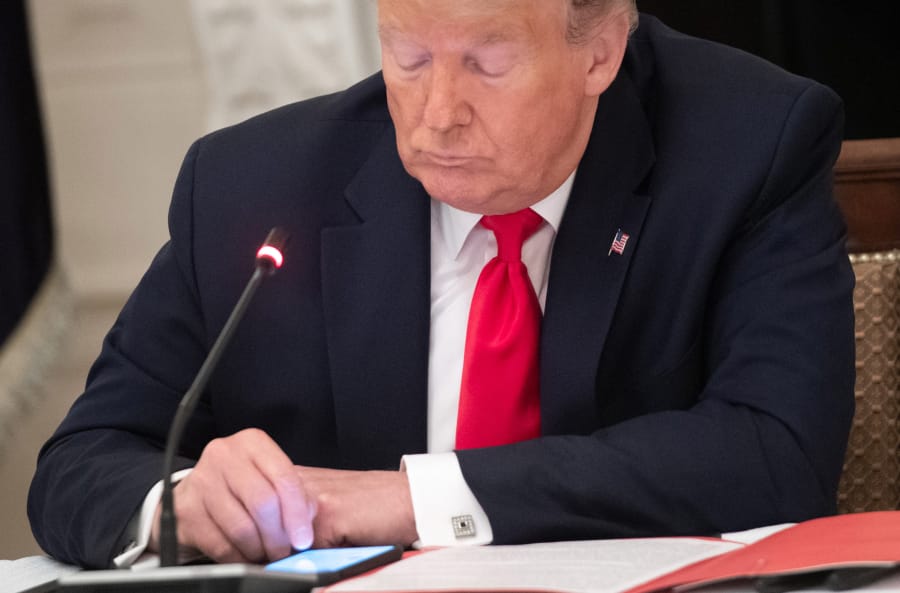 President Donald Trump uses his cellphone as he holds a roundtable discussion with governors in the State Dining Room of the White House in Washington, D.C., on June 18, 2020.