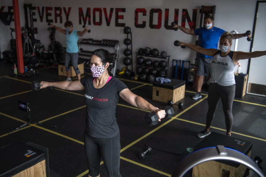 Kedie Sobeck of Los Angeles, Calif., center, works out at Burntown Fitness in east Vancouver. The studio reopened in June after Clark County entered Phase 2. It allow 5 people per class plus the instructor and has taped off sections to allow for social distancing.