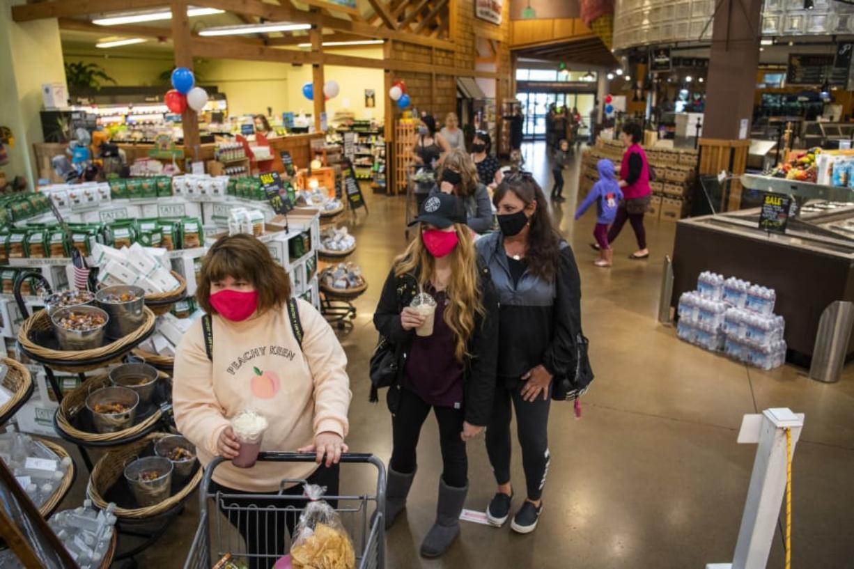 Customers line up Wednesday to check out after shopping at Chuck&#039;s Produce in Salmon Creek. Signs are posted at the entrance of the store reminding customers that face coverings are mandatory statewide.