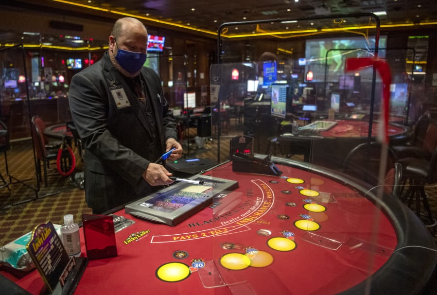 Gary Pfannes, an on-duty manager, demonstrates the use of a germicidal wand to sanitize casino chips in between use Wednesday at The Palace Casino in La Center. The Palace reopened Wednesday.