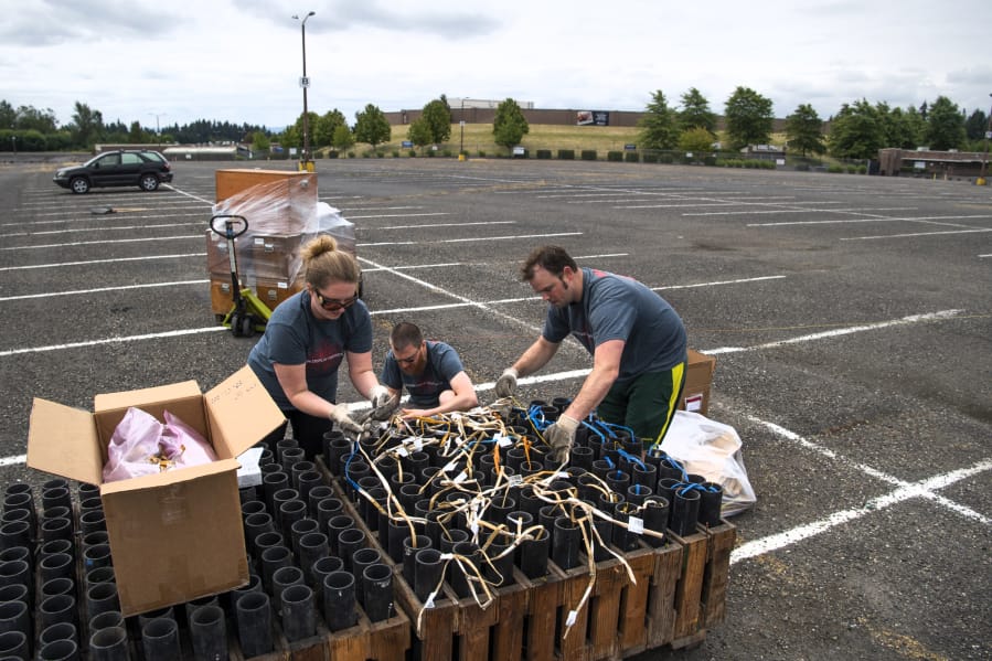 Western Display Fireworks crew member Alisa Williams, from left, pyrotechnician Reggie Edwards and lead pyrotechnician Chad Williams prepare fuses, fireworks and launchers in a parking lot at the Clark County Event Center at the Fairgrounds on Saturday. The no-audience show was to be broadcast live on Fox-12 TV for viewers to enjoy at home. Most Fourth of July fireworks events throughout the region, including the annual show at Fort Vancouver, were canceled this year due to the coronavirus pandemic.