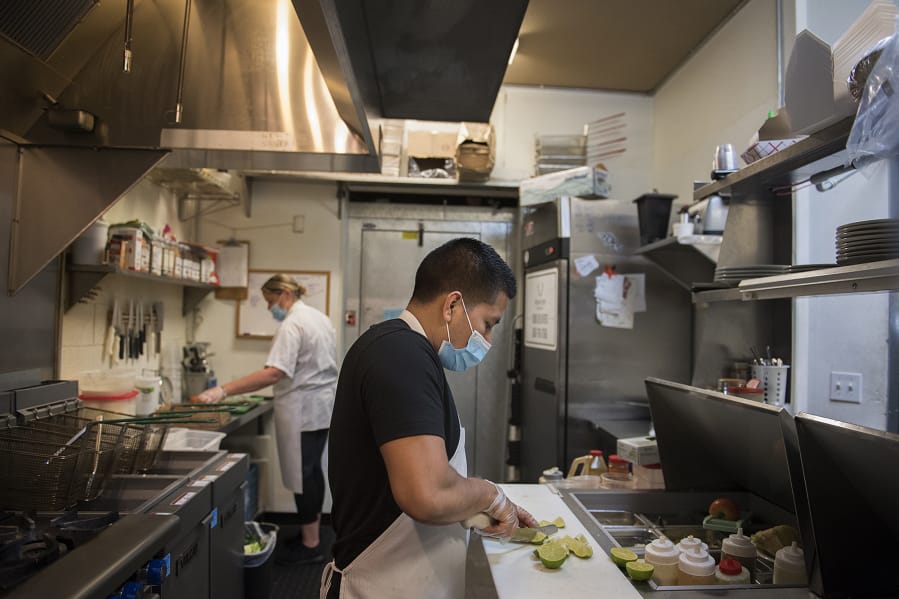 Owner Marian Adams-Manuel, background left, works with chef Vale Martinez in the busy kitchen of Frontier Public House on Tuesday. The Vancouver restaurant received Paycheck Protection Program loans to help bridge the financial gap caused by COVID-19.