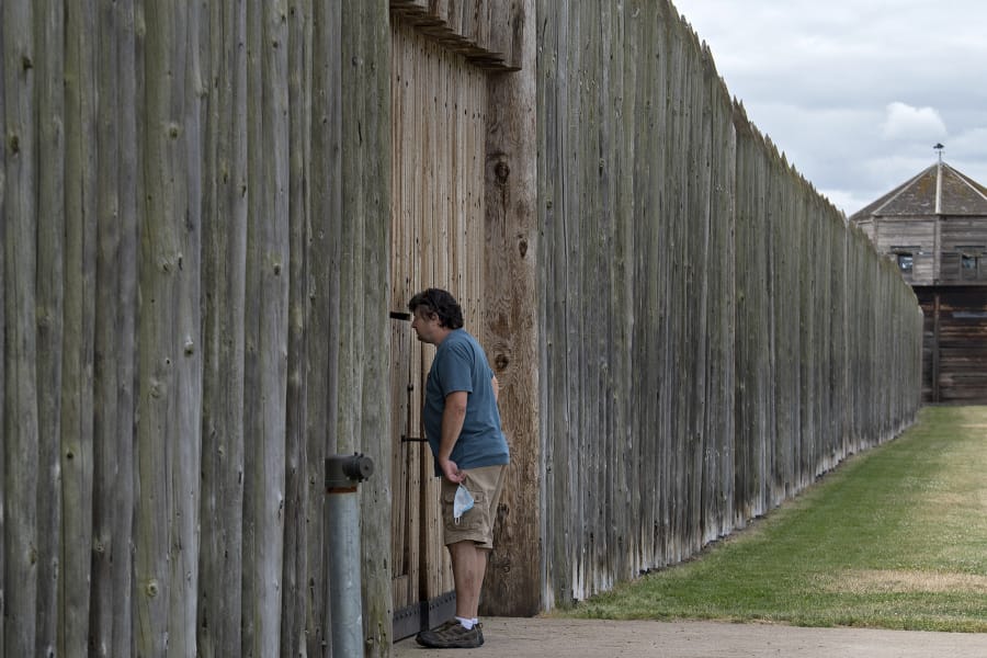 Doug Smith of Snohomish peeks through the closed front gate of the stockade at Fort Vancouver National Historic Site on Wednesday afternoon. The grounds are open, but indoor exhibits are closed.