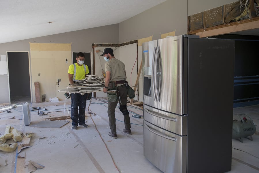 Luke Schlecht, left, and William Jones of Foxbrigade LLC lend a hand to the renovation of a kitchen at a home in Salmon Creek. Local contractors say common home areas like kitchens, family rooms, finished basements and covered patios are all in high demand while families are stuck at home during the COVID-19 pandemic.