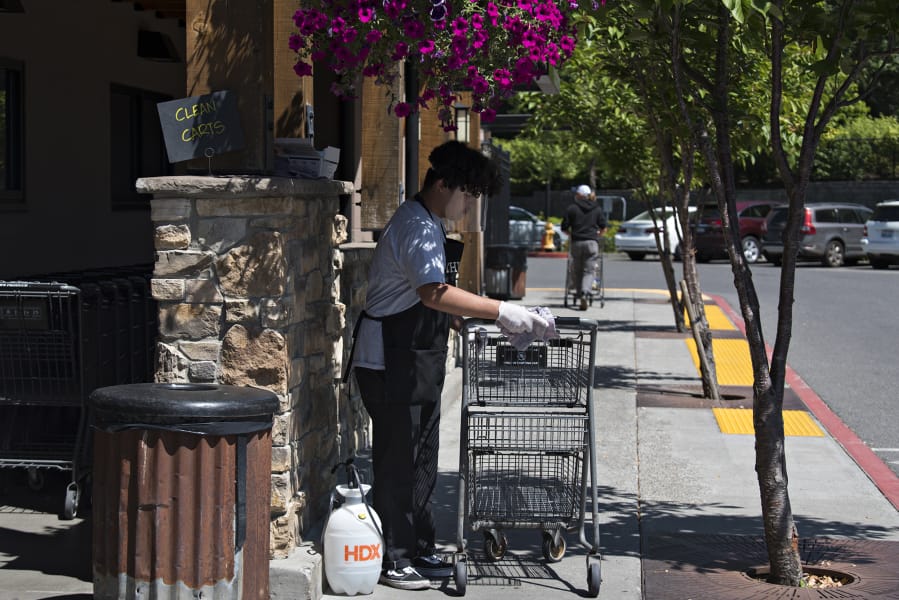 Will Chicas, an employee at Chuck's Produce & Street Market in Salmon Creek, wears a face shield as he helps disinfect carts for shoppers.