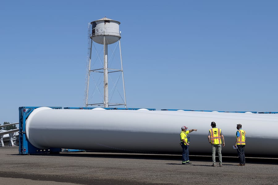 Longshore worker Jason Rasmussen, from left, talks with Zack Merrill, sales account manager for the Port of Vancouver, and Alex Strogen, the port's chief commercial officer, as they look over blades for wind turbines. The Port of Vancouver received the largest wind turbines blades ever to reach the West Coast on Monday.