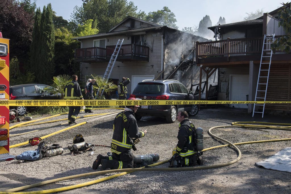Caution tape surrounds the scene as firefighters battle a blaze in two adjoining duplexes on Olive Street on Friday morning, July 31, 2020.