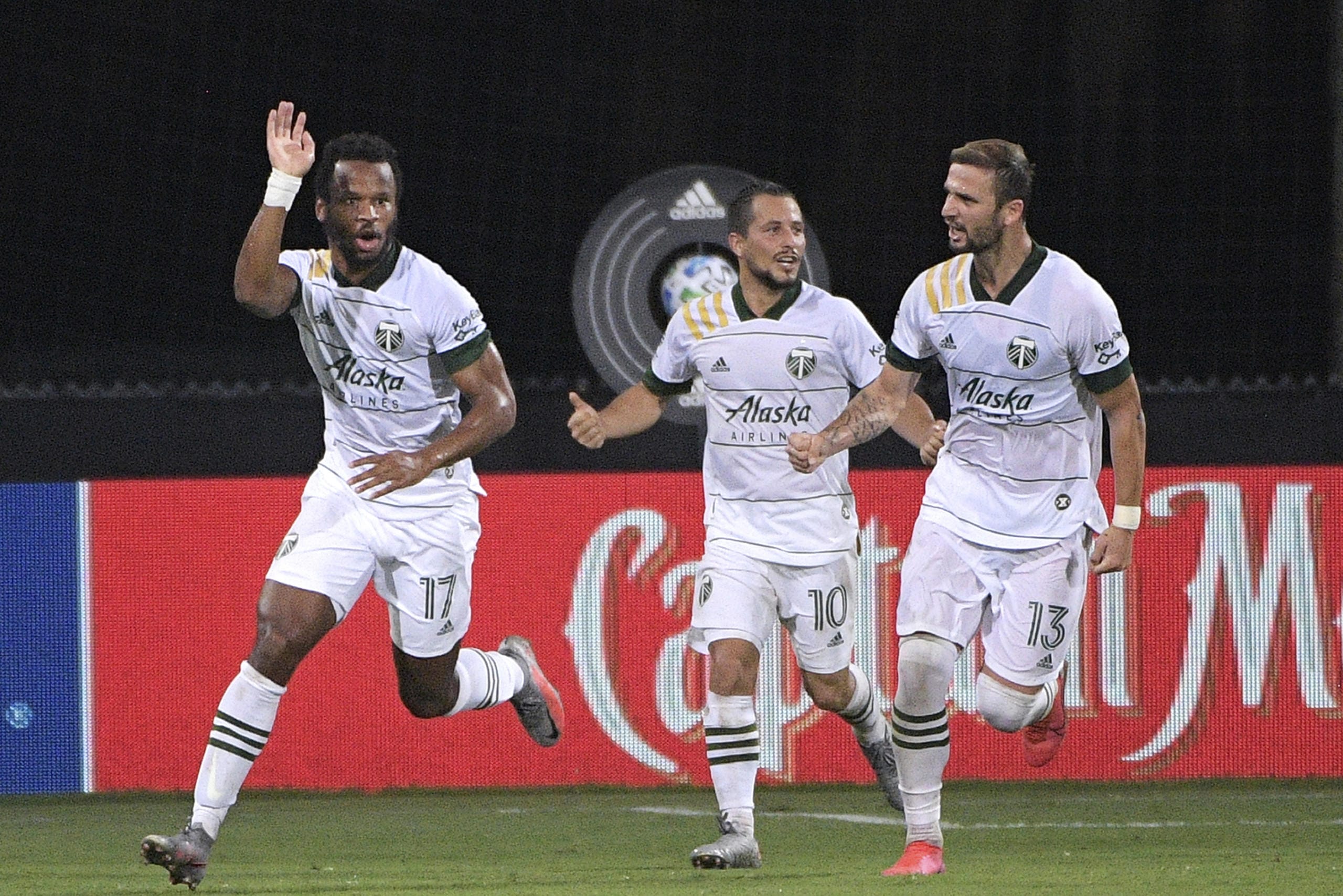 Portland Timbers forward Jeremy Ebobisse (17) celebrates after scoring a goal as midfielder Sebastian Blanco (10) and defender Dario Zuparic (13) come to congratulate him during the second half of an MLS soccer match against the Los Angeles FC, early Friday, July 24, 2020, in Kissimmee, Fla. (AP Photo/Phelan M.