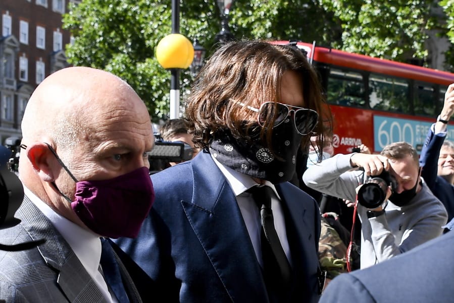 Johnny Depp, right, wearing a protective mask arrives at the Royal Court of Justice, in London, Tuesday, July 7, 2020. Johnny Depp is suing a tabloid newspaper for libel over an article that branded him a &quot;wife beater.&quot; On Tuesday, a judge at the High Court is due to begin hearing Depp&#039;s claim against The Sun&#039;s publisher, News Group Newspapers, and its executive editor, Dan Wootton, over the 2018 story alleging he was violent and abusive to then-wife Amber Heard. Depp strongly denies the claim.