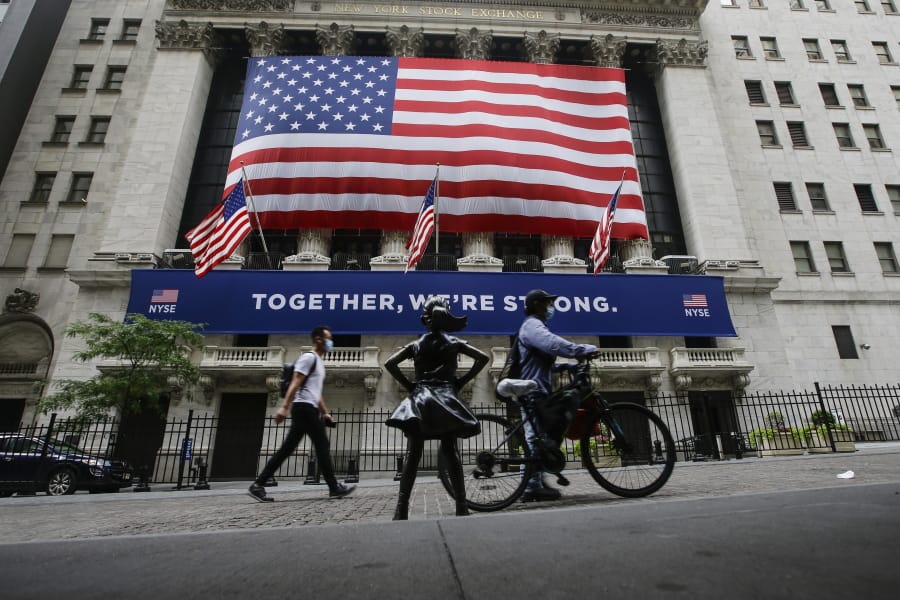 FILE - In this Tuesday, July 7, 2020 file photo, pedestrians wearing protective masks during the coronavirus pandemic pass by the New York Stock Exchange in New York.