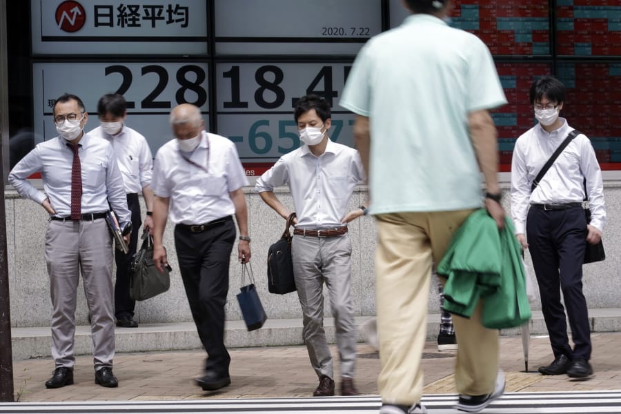 People wearing face masks walk past an electronic stock board showing Japan&#039;s Nikkei 225 index at a securities firm in Tokyo Wednesday, July 22, 2020. Shares were mixed in Asia on Wednesday, with Australia&#039;s benchmark down more than 1% on reports of a sharp rise in coronavirus cases in the Melbourne area.