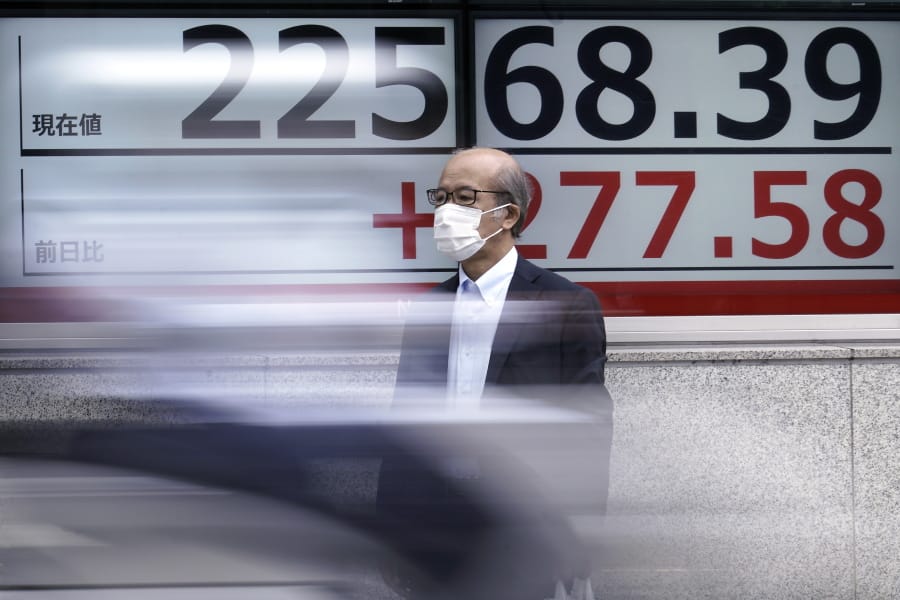 A man wearing a face mask to help curb the spread of the coronavirus stands near an electronic stock board showing Japan&#039;s Nikkei 225 index at a securities firm in Tokyo Monday, July 13, 2020.
