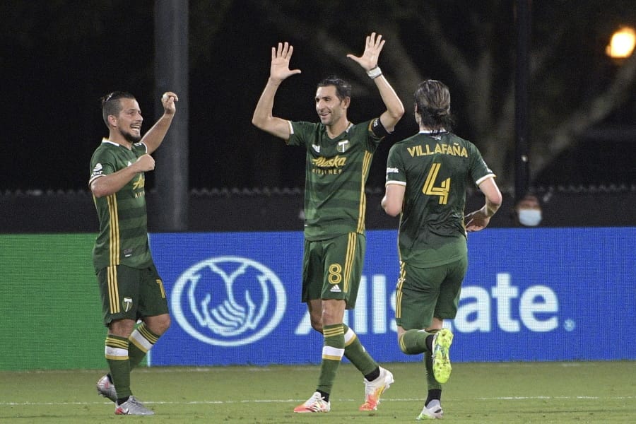 Portland Timbers midfielder Diego Valeri (8) celebrates after scoring a goal as midfielder Sebastian Blanco, left, and defender Jorge Villafana (4) come to congratulate him during the second half of an MLS soccer match against the Houston Dynamo, Saturday, July 18, 2020, in Kissimmee, Fla. (AP Photo/Phelan M.
