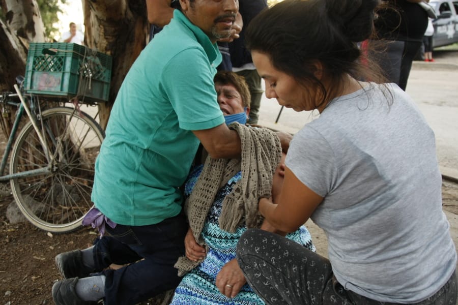 Relatives comfort a woman crying outside an unregistered drug rehabilitation center in Irapuato, Mexico, Wednesday, July 1, 2020, after gunmen burst into the facility and opened fire. According to police at least 24 people were killed in the attack.
