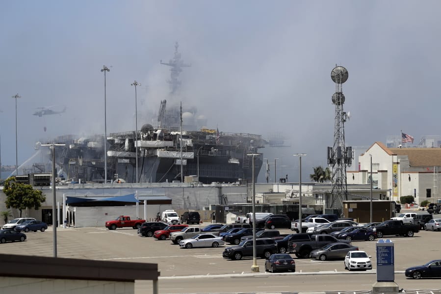 A helicopter drops water on the USS Bonhomme Richard as crews fight the fire Monday, July 13, 2020, in San Diego. Fire crews continue to battle the blaze Monday after 21 people suffered minor injuries in an explosion and fire Sunday on board the USS Bonhomme Richard at Naval Base San Diego.