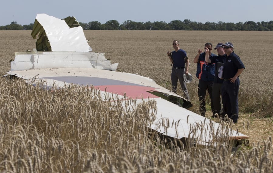 FILE - In this Friday, Aug. 1, 2014 file photo, Australian and Dutch investigators examine a piece of the Malaysia Airlines Flight 17 plane, near the village of Hrabove, Donetsk region, eastern Ukraine.