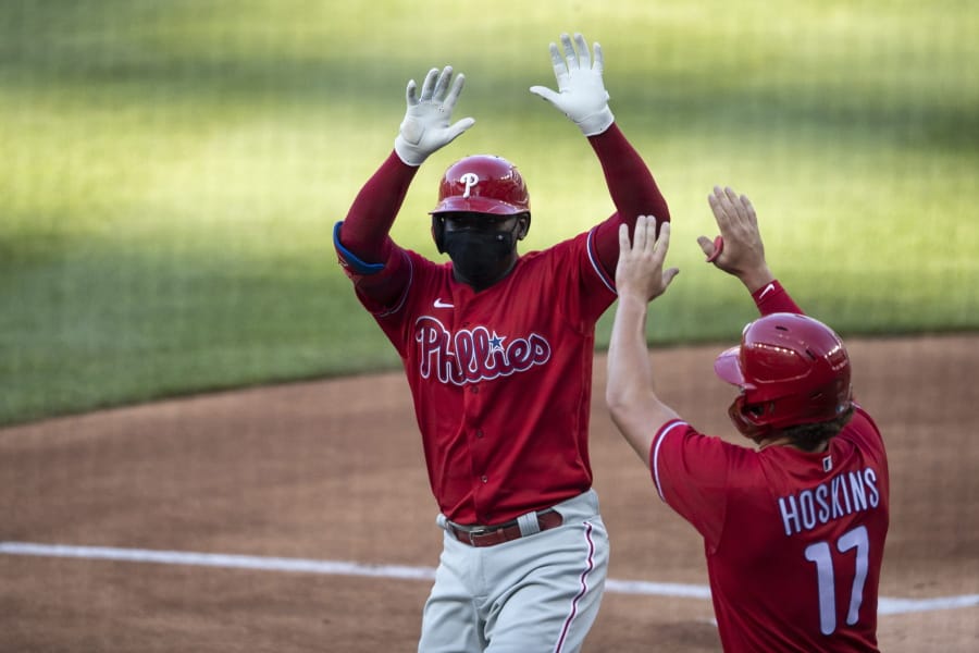 Philadelphia Phillies&#039; Didi Gregorius celebrates without touching, while wearing a mask, his three-run homer with Rhys Hoskins during the first inning of an exhibition baseball game against the Washington Nationals at Nationals Park, Saturday, July 18, 2020, in Washington.
