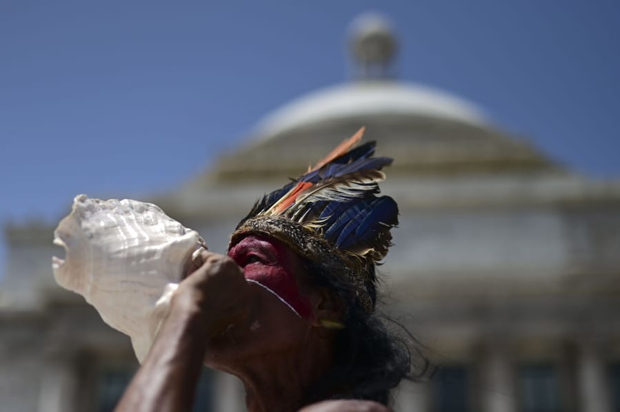 Baracutey blows on a conch shell outside the Capitol building while joining a group of activists demanding statues and street names commemorating symbols of colonial oppression be removed, in San Juan, Puerto Rico, Saturday, July 11, 2020.  Dozens of activists marched through the historic part of Puerto Rico&#039;s capital on Saturday to demand that the U.S. territory&#039;s government start by removing statues, including those of explorer Christopher Columbus.