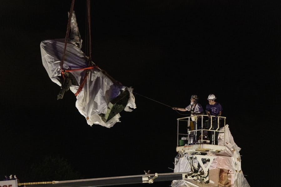 City municipal crews help guide the Christopher Columbus statue in Grant Park as it is removed by a crane, Friday, July 24, 2020, in Chicago. A statue of Christopher Columbus that drew chaotic protests in Chicago was taken down early Friday amid a plan by President Donald Trump to dispatch federal agents to the city.