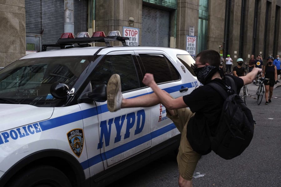 A protester kicks a police vehicle in an attempt to break its side mirror during a &quot;Solidarity with Portland&quot; protest Saturday, July 25, 2020, in New York.