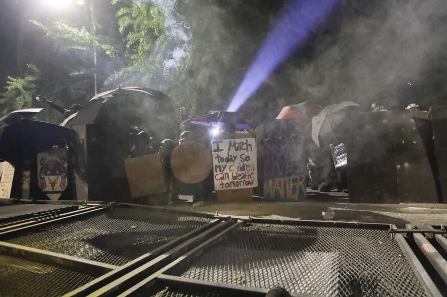 Demonstrators shield themselves behind a toppled fence as federal officers deploy tear gas during a Black Lives Matter protest at the Mark O. Hatfield United States Courthouse Sunday, July 26, 2020, in Portland, Ore.