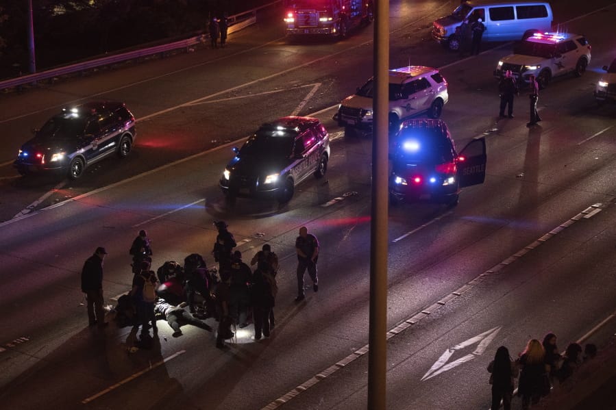 Emergency workers tend to an injured person on the ground after a driver sped through a protest-related closure on the Interstate 5 freeway in Seattle, authorities said early Saturday, July 4, 2020. Dawit Kelete, 27, has been arrested and booked on two counts of vehicular assault.