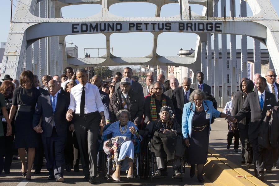 FILE - In this March 7, 2015, file photo, singing &quot;We Shall Overcome,&quot; President Barack Obama, third from left, walks holding hands with Amelia Boynton, who was beaten during &quot;Bloody Sunday,&quot; as they and the first family and others including Rep. John Lewis, D-Ga, left of Obama, walk across the Edmund Pettus Bridge in Selma, Ala., for the 50th anniversary of &quot;Bloody Sunday,&quot; a landmark event of the civil rights movement. Some residents in the landmark civil rights city of Selma, Ala., are among the critics of a bid to rename the historic bridge where voting rights marchers were beaten in 1965.