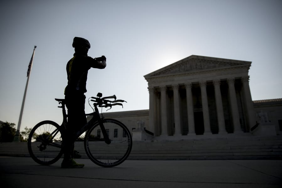 A man on a bicycle stops to take a photograph outside the Supreme Court, Wednesday, July 8, 2020, in Washington.