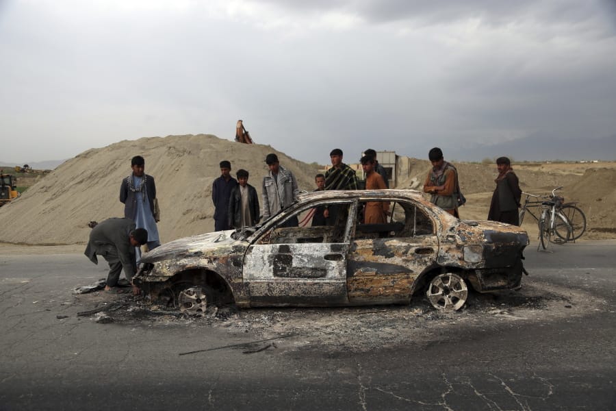 FILE - In this April 9, 2019, file photo, Afghans watch a civilian vehicle burnt after being shot by U.S. forces following an attack near the Bagram Air Base, north of Kabul, Afghanistan. Three American service members and a U.S. contractor were killed when their convoy hit a roadside bomb on Monday near the main U.S. base in Afghanistan, the U.S. forces said. The Taliban claimed responsibility for the attack. Intelligence alleging that Afghan militants might have accepted Russian bounties for killing American troops didn&#039;t scuttle the U.S.-Taliban agreement or President Donald Trump&#039;s plan to withdraw thousands more troops from the war.
