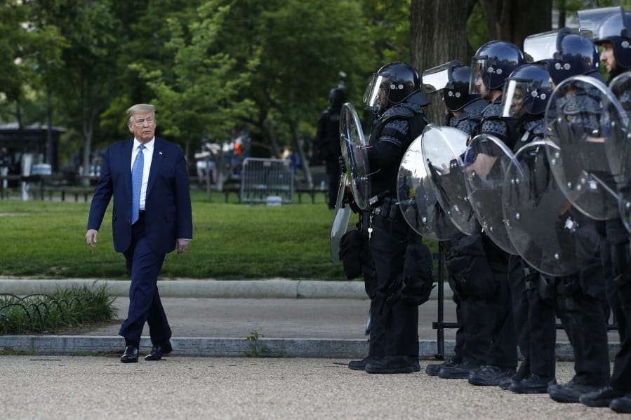 FILE - In this June 1, 2020, file photo President Donald Trump walks past police in Lafayette Park after visiting outside St. John&#039;s Church across from the White House in Washington.  When it comes to squelching protests in Democrat-run cities, Trump is eager to send in federal troops and agents -- even when local leaders are begging him to butt out.