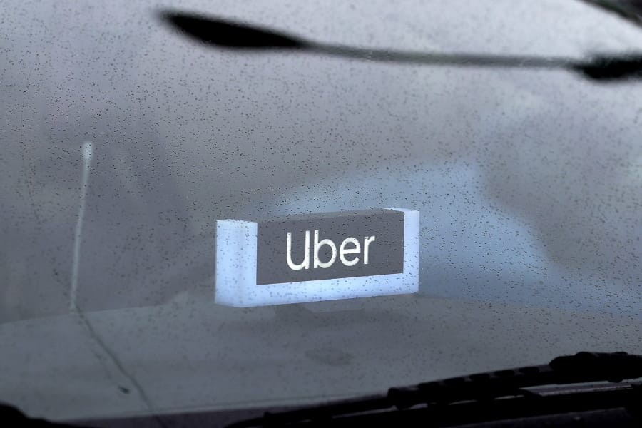FILE - In this May 15, 2020 file photo, an Uber sign is displayed inside a car in Chicago. Uber finally got its food delivery company, acquiring Postmates in a $2.65 billion all-stock deal, the ride-hailing giant confirmed Monday, July 6.  (AP Photo/Nam Y.